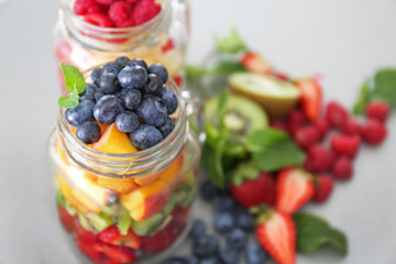 Mason jar with fruits and berries on table, closeup
