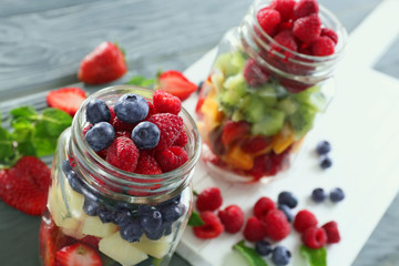 Jars with fruits and berries on table, closeup