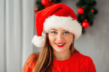 Young beautiful girl in christmas hat looks at camera