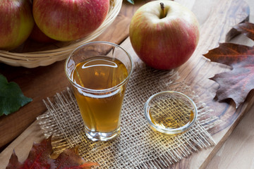 Apple cider vinegar in a glass, with apples in the background