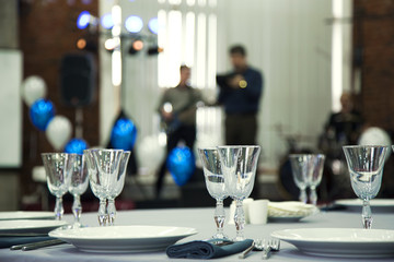 Preparation for a banquet. The tables are covered with a tablecloth. Wine glasses are on the tables in the restaurant.