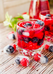 Summer berry lemonade with frozen berries on a wooden rustic table, selective focus