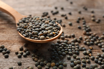 Spoon with green lentils on wooden table