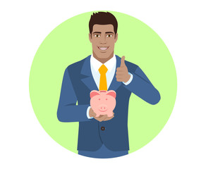 Businessman holding a piggy bank and showing thumb up