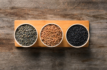 Bowls with different lentils on wooden table