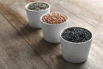Bowls with different lentils on wooden table