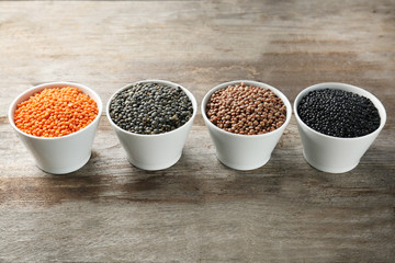 Bowls with different lentils on wooden table