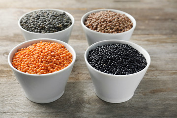 Bowls with different lentils on wooden table