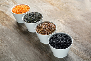 Bowls with different lentils on wooden table