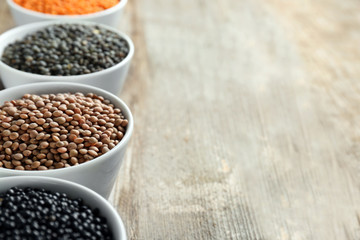 Bowls with different lentils on wooden table