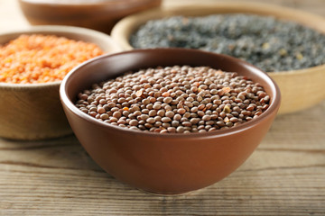 Bowl with brown lentils on wooden table