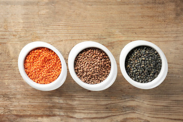 Bowls with different lentils on wooden table