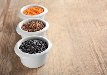 Bowls with different lentils on wooden table