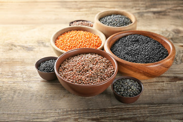 Bowls with different lentils on wooden table