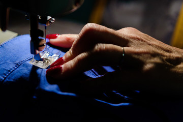 Close up on sewing machine and seamstress' hand while she is working