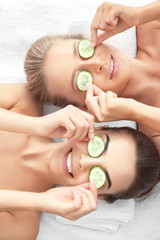 Young women with cucumber slices in spa salon