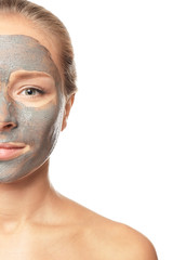 Young woman with facial mask on white background