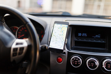 The map on the phone in the background of the dashboard. Black mobile phone with map gps navigation...