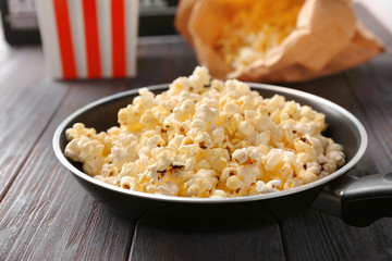 Frying pan with popcorn on wooden table