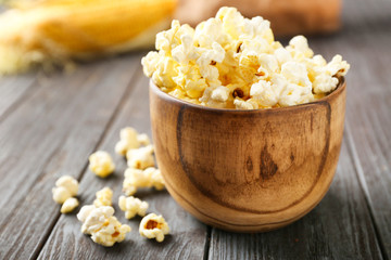 Bowl with popcorn on wooden table