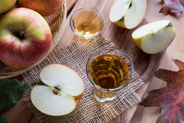 Apple cider vinegar in a glass, with apples in the background