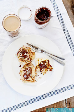 Pancakes with chocolate and coffee on white textile outdoor
