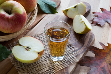 Apple cider vinegar in a glass, with apples in the background