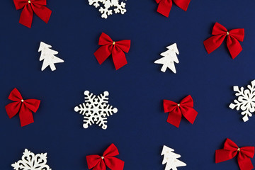 Holiday postcard. Christmas pattern of red bows and white snowflakes and xmas trees on a dark blu background
