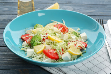 Plate with tasty vegetable salad on wooden table