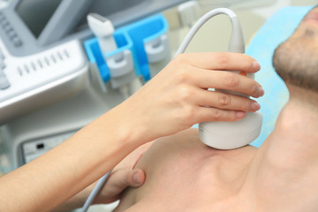 Doctor conducting ultrasound examination of patient's shoulder in clinic