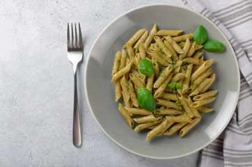 Pasta with homemade pesto sauce in a white plate on a light-blue