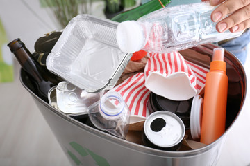 Young woman throwing plastic bottle into litter bin, close up