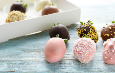 Tasty chocolate dipped and glazed strawberries on wooden background