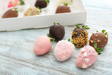 Tasty chocolate dipped and glazed strawberries on wooden background