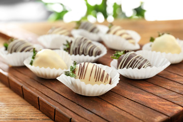 Tasty chocolate dipped strawberries on wooden board, closeup