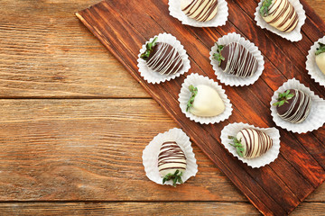 Tasty chocolate dipped strawberries on wooden board