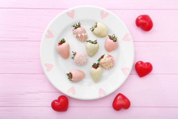 Plate with tasty glazed strawberries on wooden table