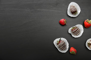 Tasty chocolate dipped strawberries on dark table