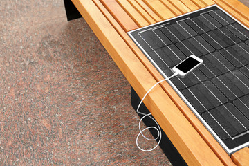 Mobile phone charging on bench with solar panel