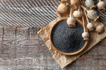 Poppy heads and plate with seeds on wooden table