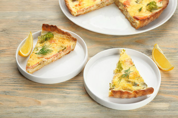 Plates with pieces of tasty salmon quiche on table