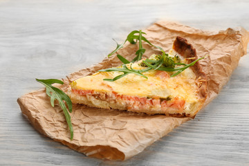 Piece of tasty salmon quiche on table