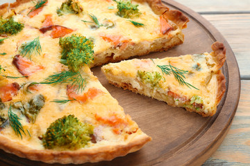 Tasty salmon quiche on wooden board, closeup