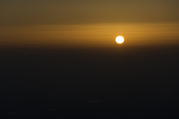 Sunset hot yellow and red sky. Sun is hidding behind clouds.