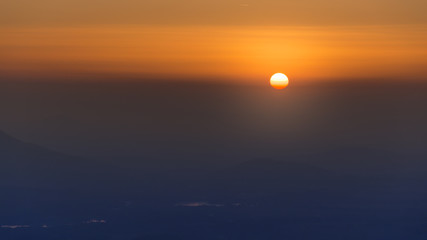 Sunset hot yellow and red sky. Sun is hidding behind clouds.
