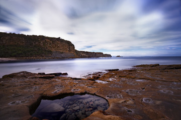 Fototapeta na wymiar Rugged coastline with still rock pool in the foreground