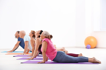 Group of mature men and women at yoga lesson indoors