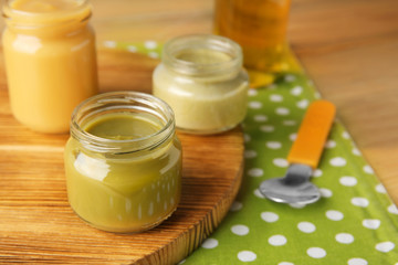 Board with jars of tasty baby food on table