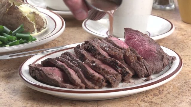 Pouring Au jus on beef sirloin pot roast