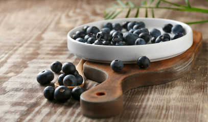 Plate with fresh acai berries on wooden table
